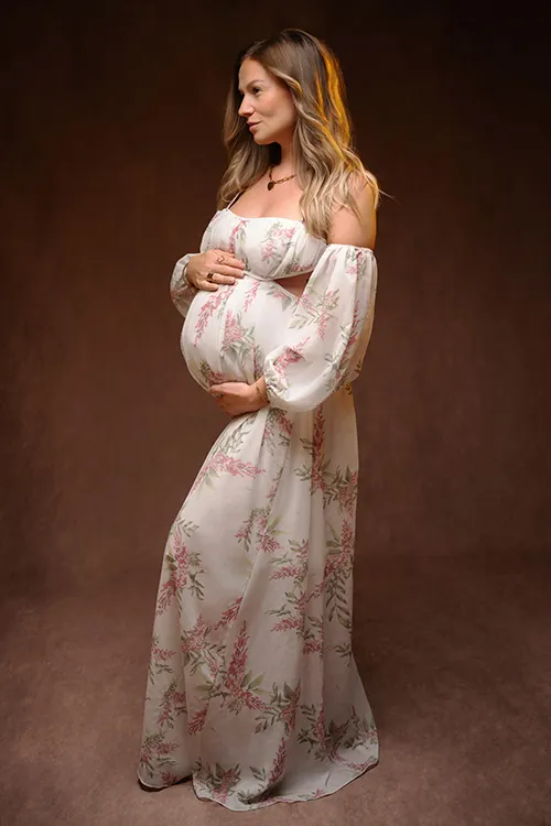 Future maman en robe fleurie, séance maternité en studio fond brun, photographe Nantes