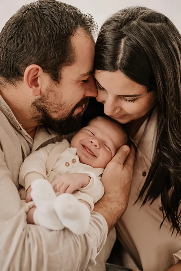 Nouveau-né souriant blotti contre ses parents, photographe bébé près de Nantes